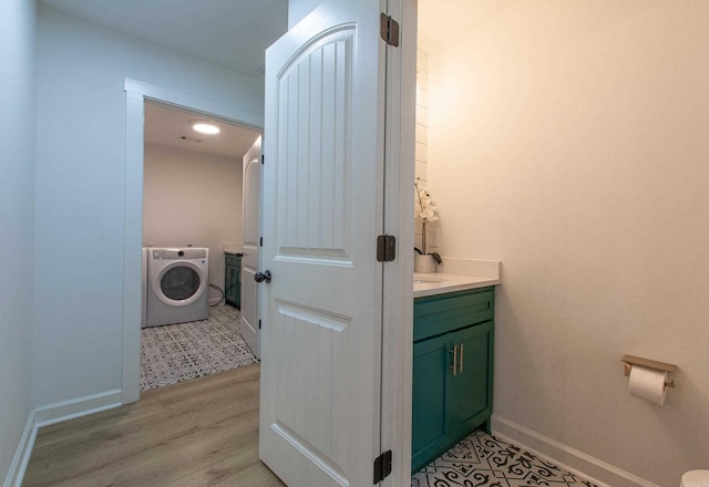 clothes washing area featuring laundry area, washer / dryer, baseboards, and light wood-type flooring