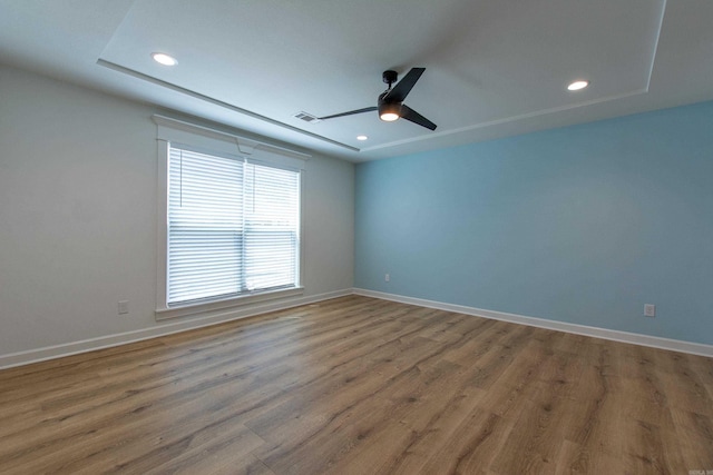 spare room with baseboards, ceiling fan, wood finished floors, and visible vents