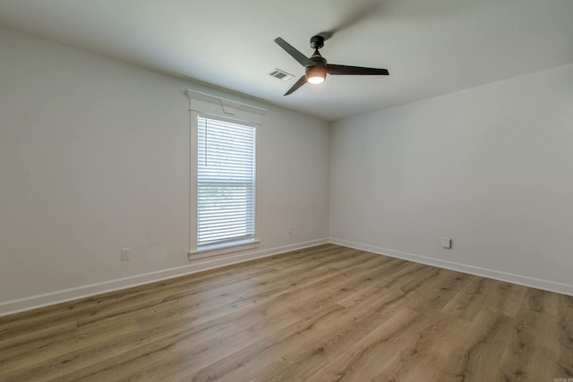 empty room featuring a ceiling fan, baseboards, visible vents, and light wood-type flooring