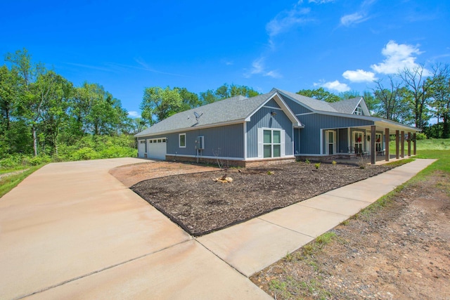 view of side of home featuring covered porch, an attached garage, driveway, and a shingled roof