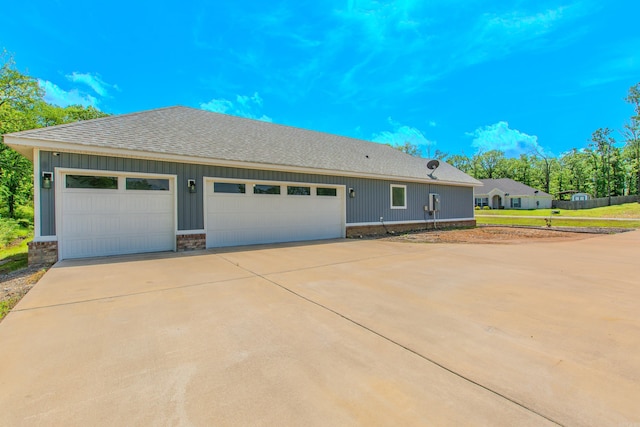 view of front facade featuring concrete driveway, board and batten siding, a shingled roof, and a garage