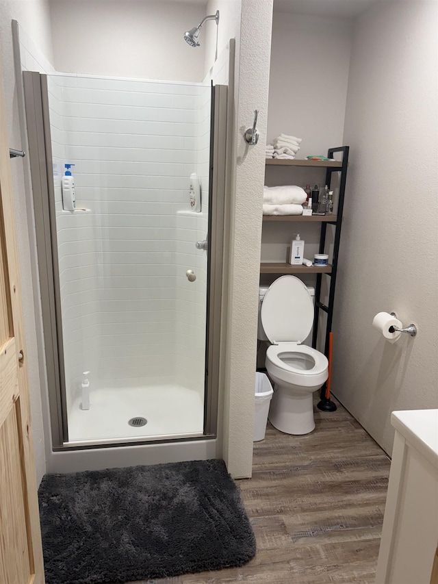 bathroom with toilet, a shower stall, wood finished floors, and vanity