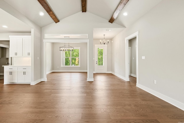 unfurnished living room featuring baseboards, vaulted ceiling with beams, wood finished floors, and a notable chandelier