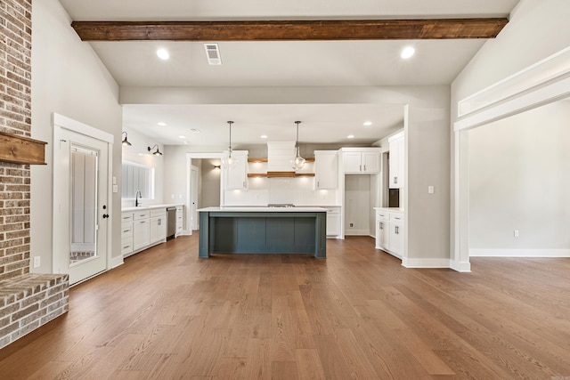 kitchen with white cabinetry, wood finished floors, beam ceiling, and dishwasher