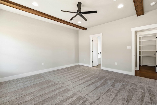 unfurnished bedroom featuring a walk in closet, carpet floors, baseboards, beamed ceiling, and recessed lighting