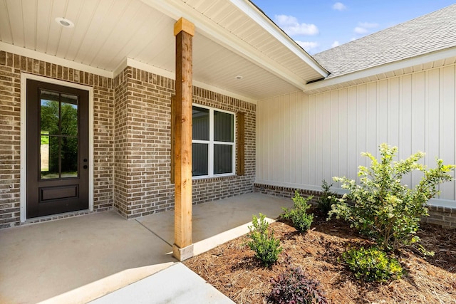 entrance to property featuring brick siding and a shingled roof