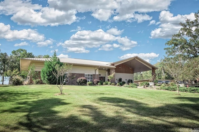 rear view of property featuring brick siding, a yard, and metal roof