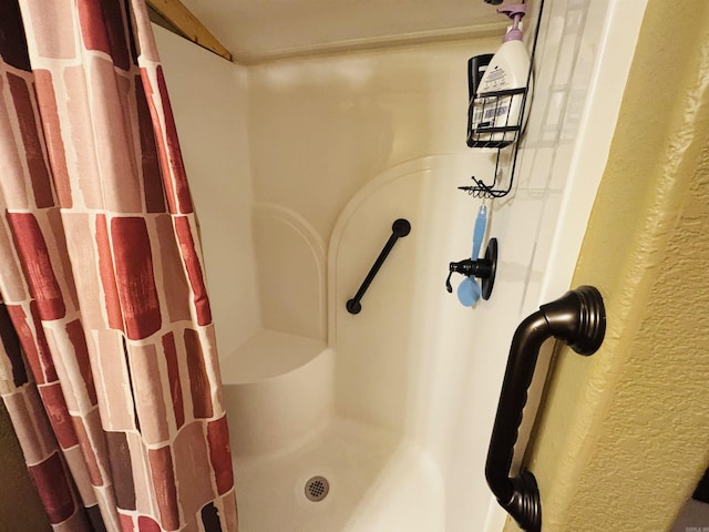 bathroom featuring a textured wall and a shower stall