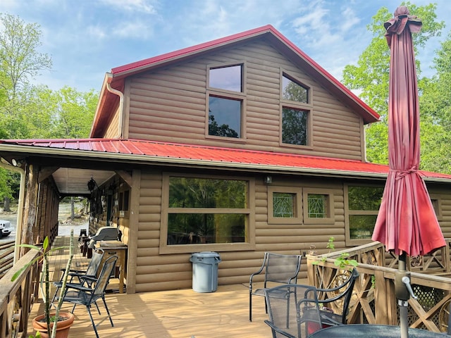 back of property featuring faux log siding, a deck, and metal roof