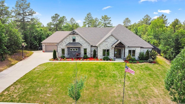 french country style house with roof with shingles, brick siding, a garage, a front yard, and concrete driveway