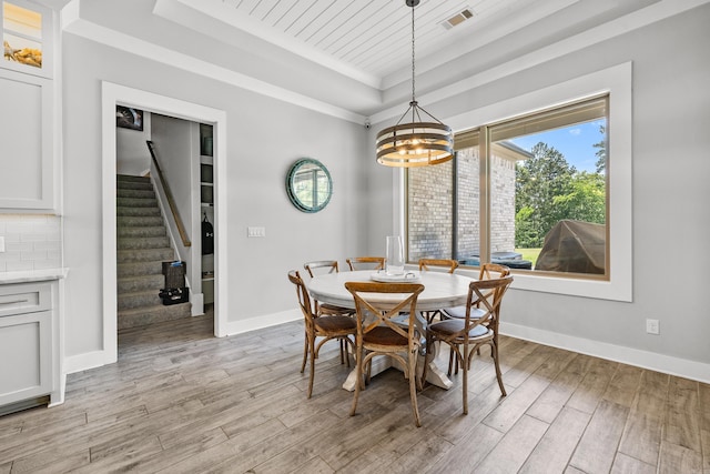 dining room with visible vents, light wood-style flooring, a tray ceiling, and an inviting chandelier