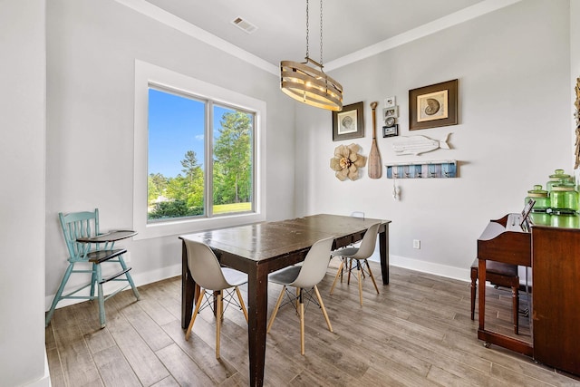 dining area with baseboards, visible vents, ornamental molding, and wood finished floors