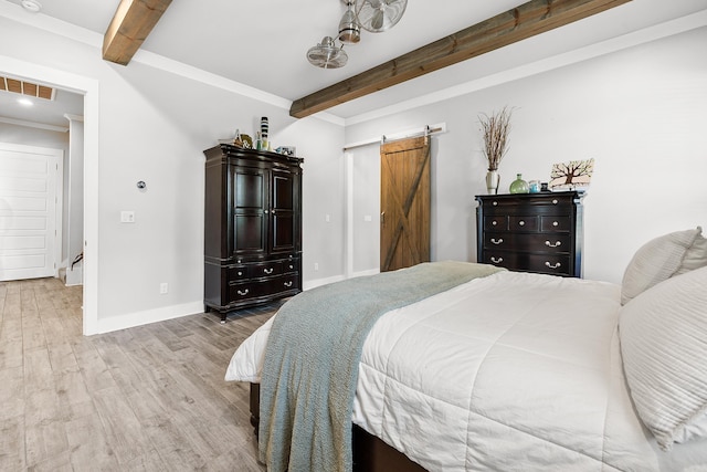 bedroom with baseboards, a barn door, beam ceiling, and wood finished floors