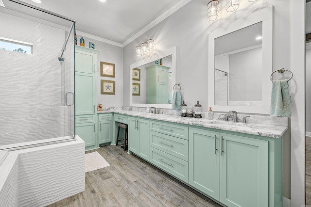 bathroom with double vanity, wood finished floors, a sink, ornamental molding, and a shower with door