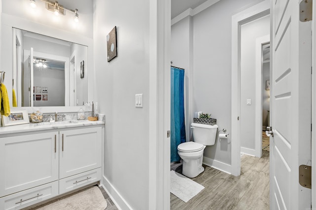 bathroom featuring ceiling fan, vanity, toilet, baseboards, and wood finished floors
