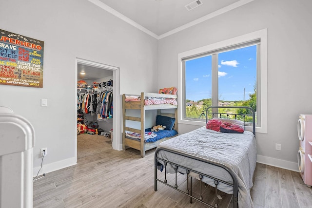 bedroom with visible vents, ornamental molding, a walk in closet, and multiple windows