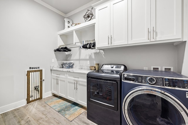 washroom featuring crown molding, light wood-style flooring, cabinet space, and washing machine and clothes dryer