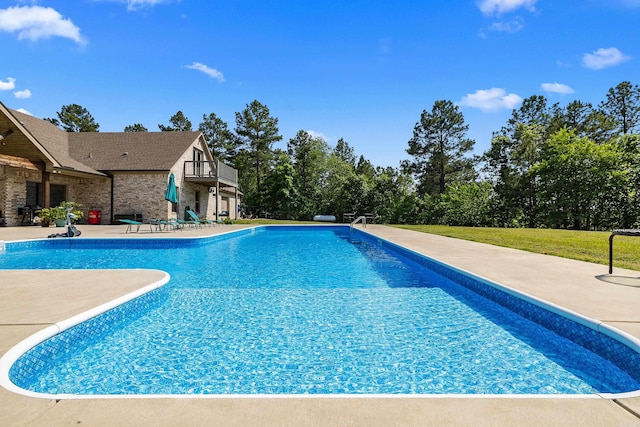 outdoor pool with a lawn and a patio