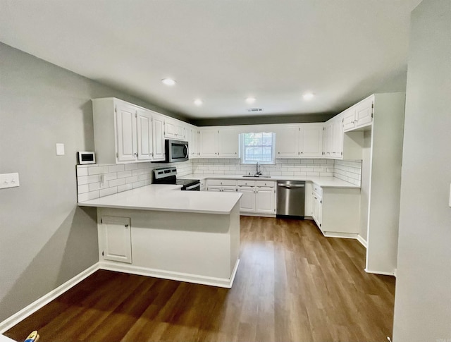 104 Louis, Searcy, AR 72143 - kitchen with decorative backsplash, a peninsula, a sink, dark wood finished floors, and appliances with stainless steel finishes