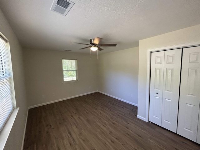 unfurnished bedroom with visible vents, baseboards, and dark wood-style floors