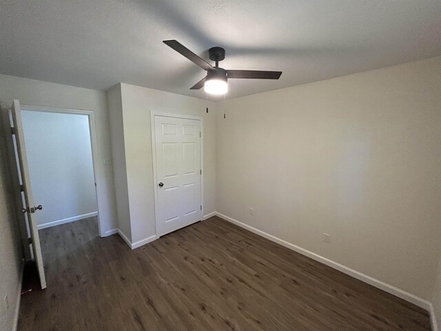 unfurnished bedroom featuring dark wood-type flooring, a ceiling fan, and baseboards