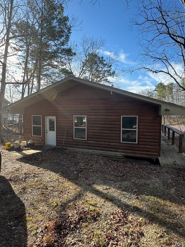 back of house featuring faux log siding and a deck