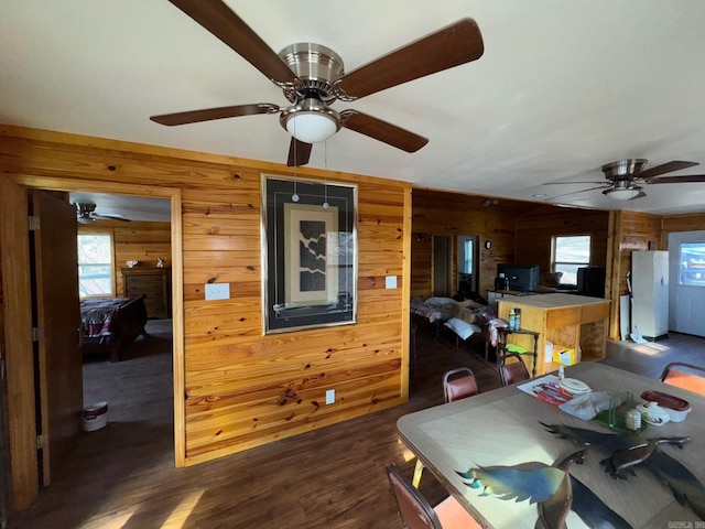 dining area featuring dark wood-type flooring, wood walls, and ceiling fan