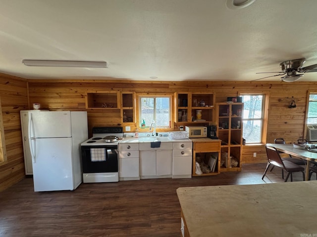 kitchen featuring white appliances, wooden walls, white cabinets, and a sink