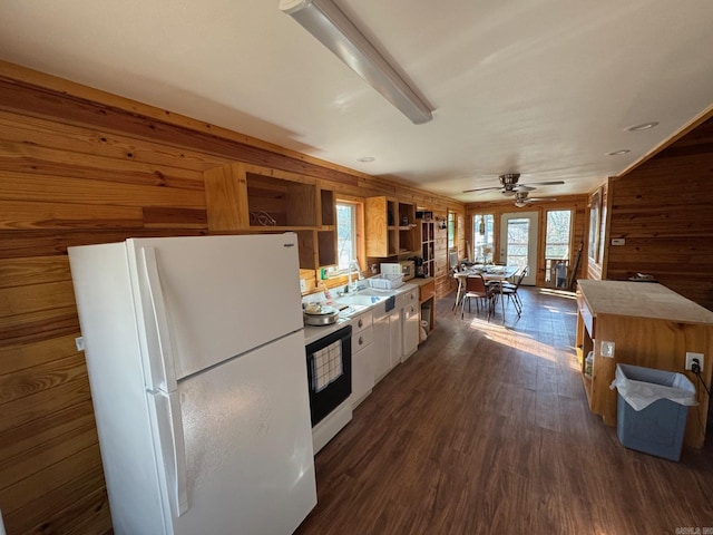 kitchen featuring dark wood-style flooring, open shelves, a sink, white appliances, and wood walls