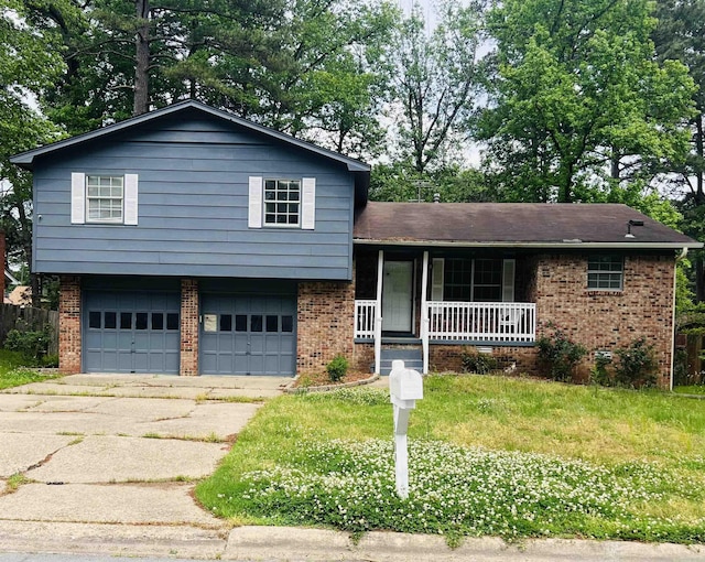 split level home with a garage, covered porch, driveway, and brick siding