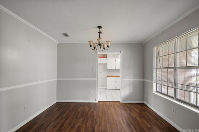 spare room featuring visible vents, wood finished floors, baseboards, an inviting chandelier, and ornamental molding