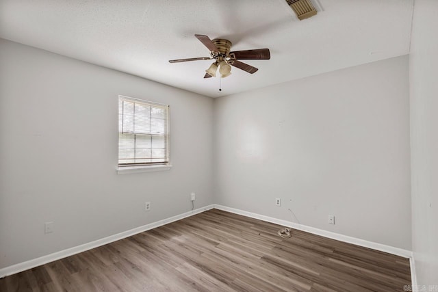 unfurnished room with baseboards, ceiling fan, wood finished floors, and visible vents