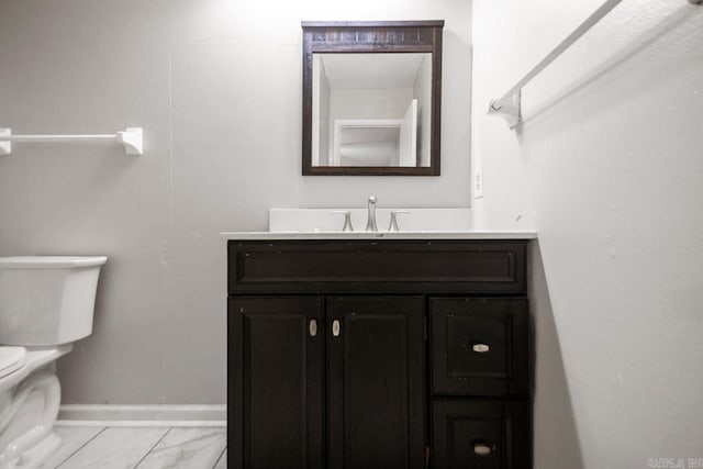 half bathroom with vanity, marble finish floor, baseboards, and toilet