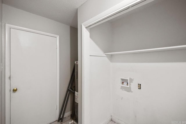 laundry area with a textured ceiling, washer hookup, and water heater