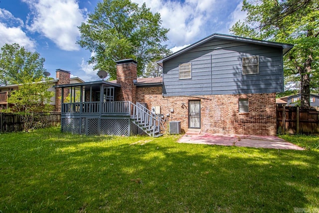 back of property with a lawn, a deck, a patio area, brick siding, and a fenced backyard
