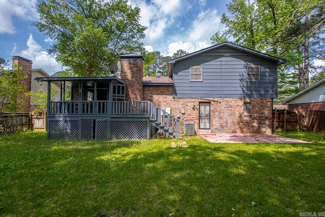 back of property with a yard, brick siding, and fence