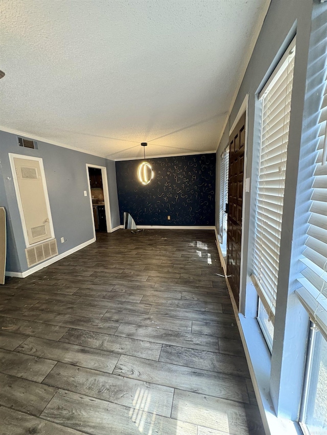 unfurnished living room featuring wood finished floors, baseboards, a textured ceiling, and visible vents