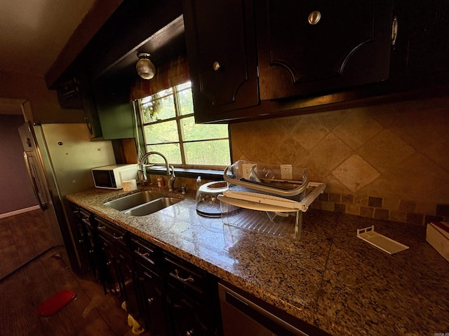 kitchen featuring stone countertops, a sink, decorative backsplash, and white microwave