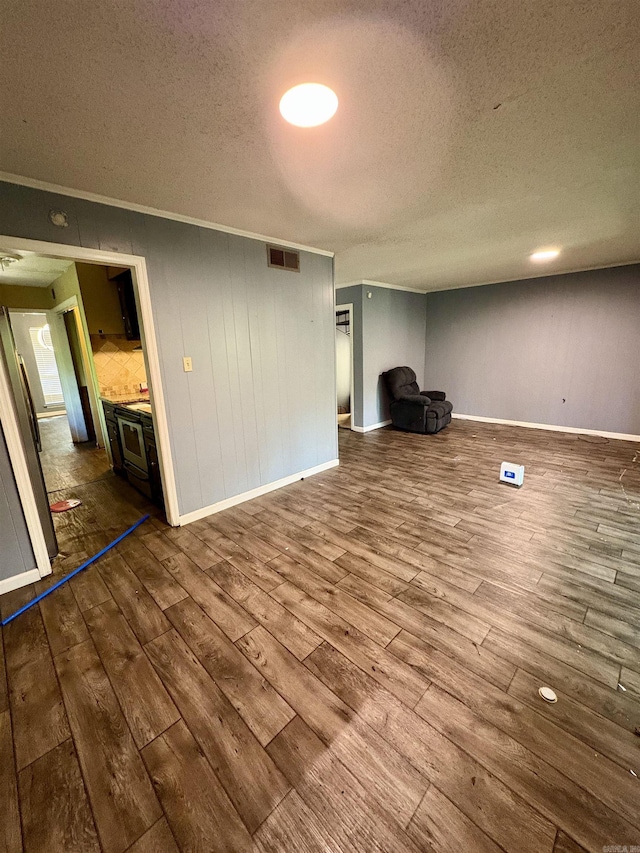 unfurnished living room featuring ornamental molding, dark wood-style flooring, a textured ceiling, and visible vents
