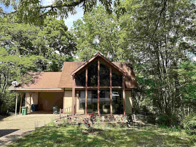 back of house with stucco siding and gravel driveway