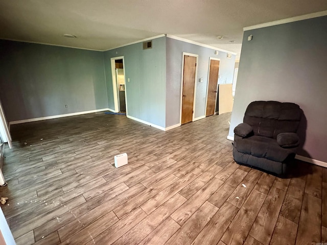 interior space with crown molding, baseboards, wood finished floors, and visible vents