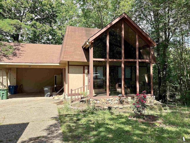 rear view of house with roof with shingles, an attached carport, and aphalt driveway