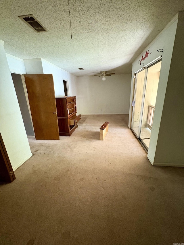 carpeted spare room featuring a ceiling fan, a textured ceiling, and visible vents