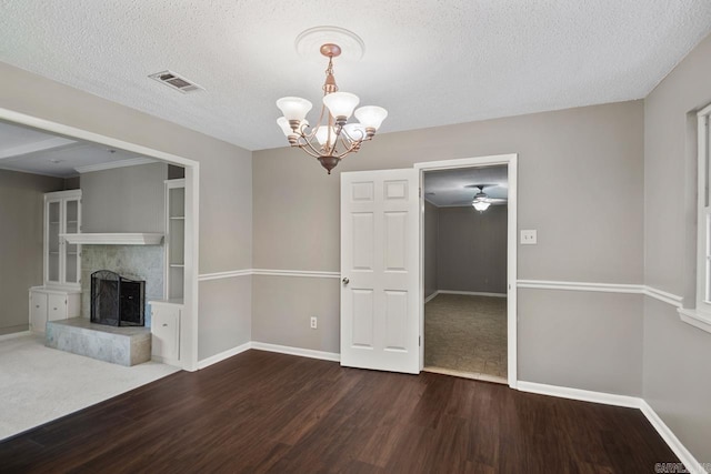 unfurnished dining area with an inviting chandelier, a textured ceiling, baseboards, wood finished floors, and visible vents