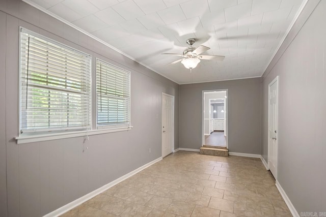 spare room with baseboards, ornamental molding, and ceiling fan