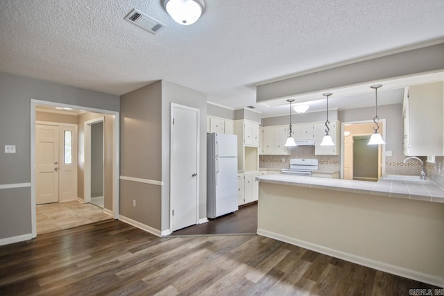 kitchen featuring visible vents, freestanding refrigerator, electric range, tile countertops, and a sink