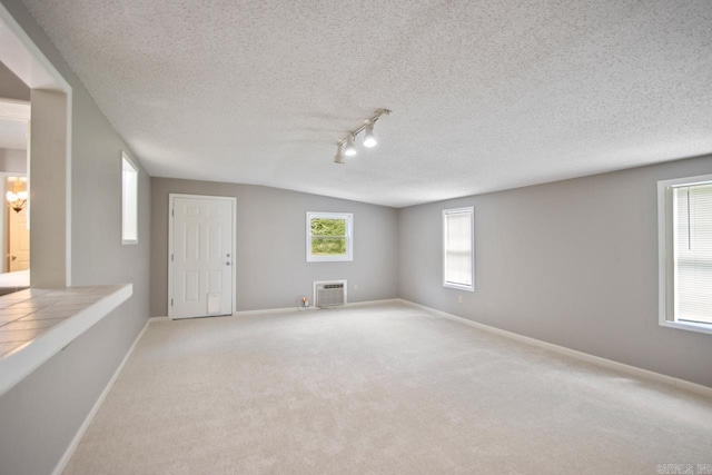 unfurnished room with carpet floors, a textured ceiling, baseboards, and track lighting
