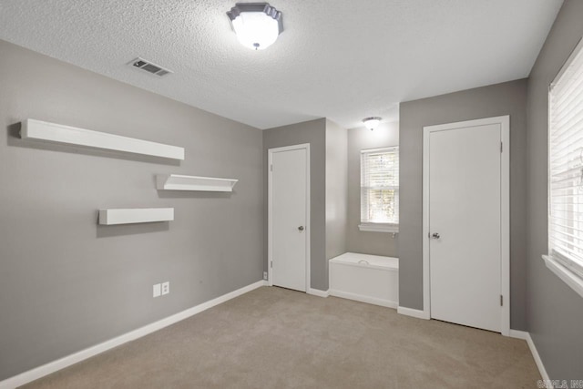 unfurnished bedroom with visible vents, carpet flooring, baseboards, and a textured ceiling