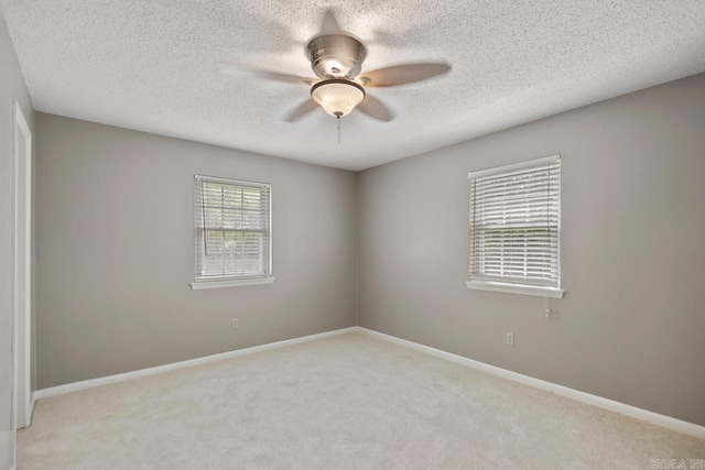 carpeted spare room with baseboards, a textured ceiling, and ceiling fan
