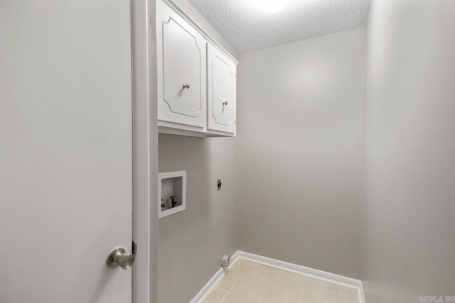 washroom featuring electric dryer hookup, a textured ceiling, cabinet space, baseboards, and hookup for a washing machine